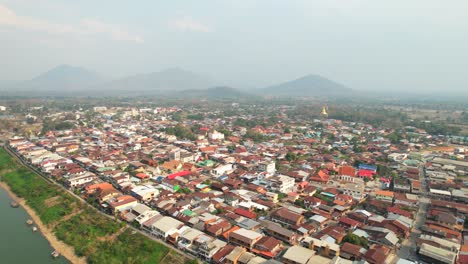 Toma-Aérea-De-Hileras-De-Casas-Residenciales-En-El-Distrito-De-Chiang-Khan-Junto-A-La-Orilla-Del-Río-Mekong-En-Tailandia