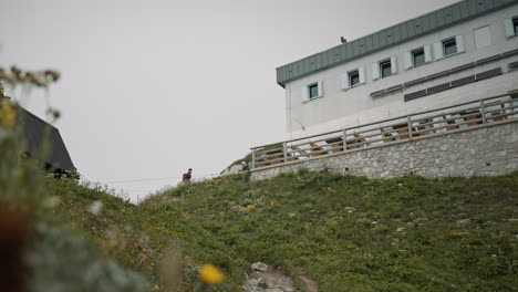 low perspective of a hiker walking in a distance towards the benches in front a mountain cottage on mountain črna prst