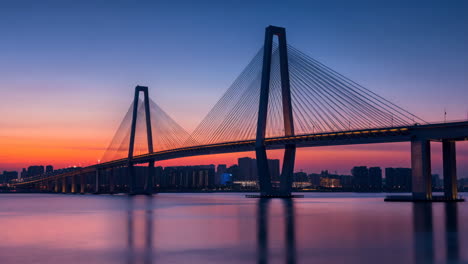 vibrant sunset colors over a modern cable-stayed bridge and city skyline