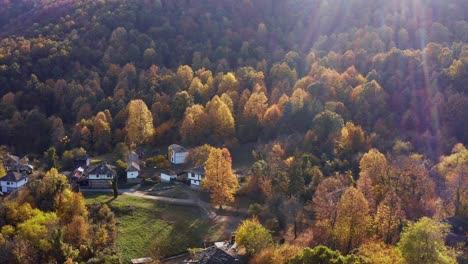 Schönes-Herbstsonnenlicht,-Bulgarisches-Dorf,-Bunter-Wald,-Drohnenaufnahme