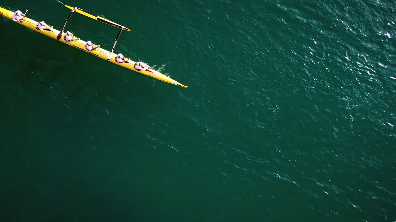 hermosa antena de cámara lenta sobre una canoa de balancín remada en agua azul