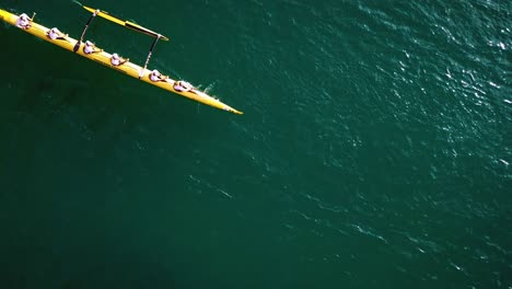 Hermosa-Antena-De-Cámara-Lenta-Sobre-Una-Canoa-Con-Estabilizadores-Remando-En-Agua-Azul