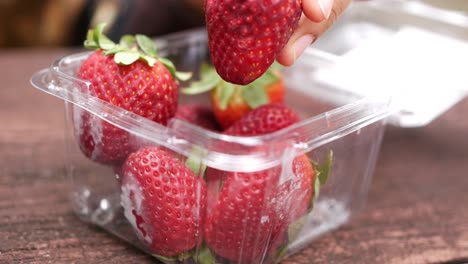 Hand-pick-a-ripe-red-strawberries-from-a-plastic-packet-,