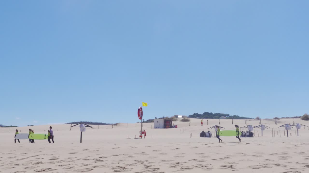 pocos grupos de surfistas llevando sus tablas de surf en praia do guincho, portugal