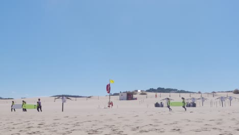 pocos grupos de surfistas llevando sus tablas de surf en praia do guincho, portugal