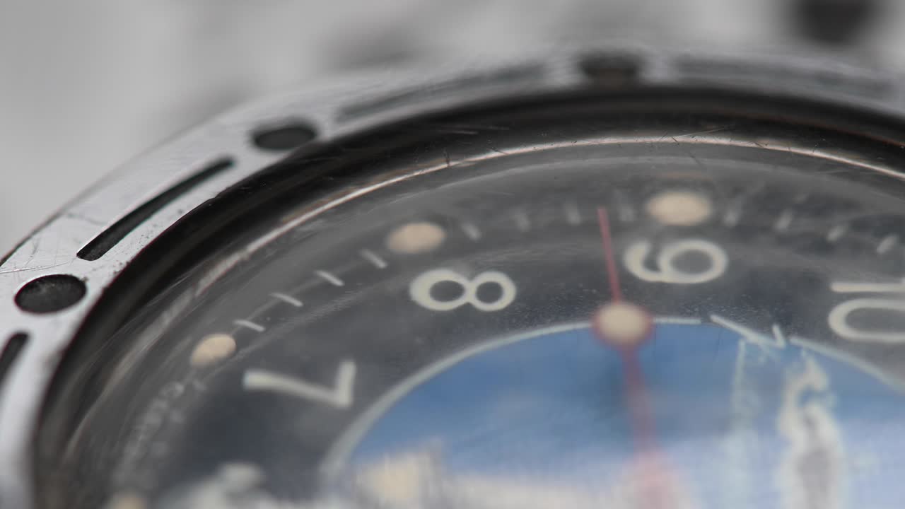 primer plano de poca profundidad de campo. el movimiento de la aguja de segundos a través del vidrio fangoso de un viejo reloj de pulsera