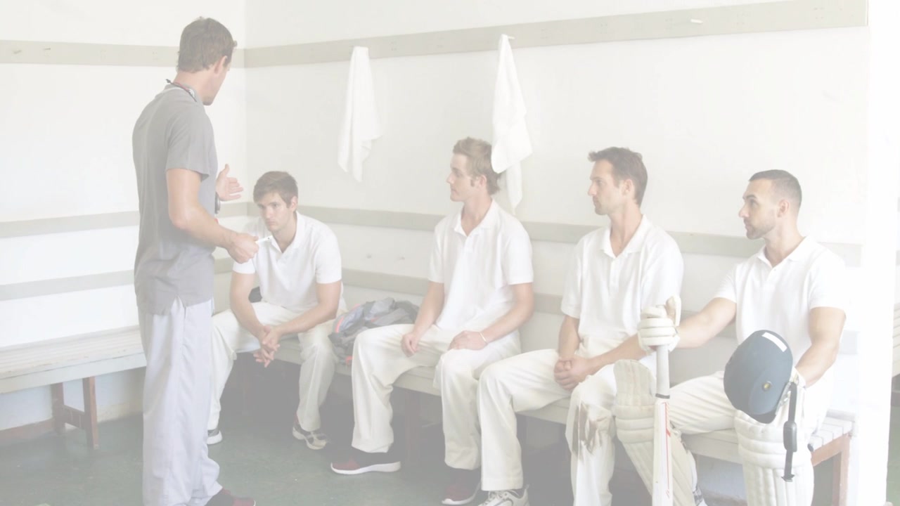 Træner nærmer sig bænken med papir og coacher cricket hold med bat og hjelm til briefing.