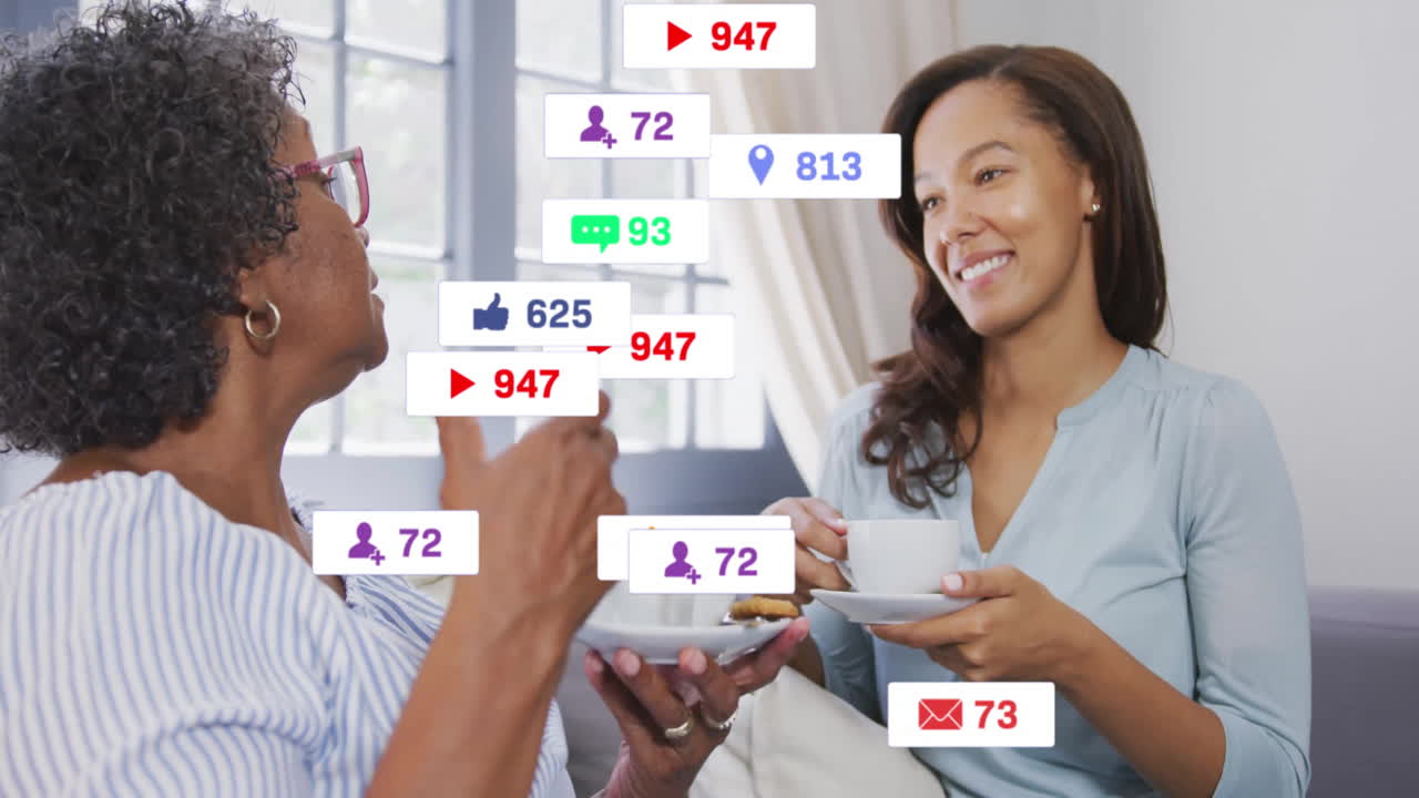 Two women sharing tea and cookies in bright living room, with floating digital social media icons
