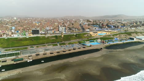 Vista-Aérea-Inclinada-Hacia-La-Costa-De-La-Soleada-Ciudad-De-Huacho,-Día-Brumoso-En-Perú