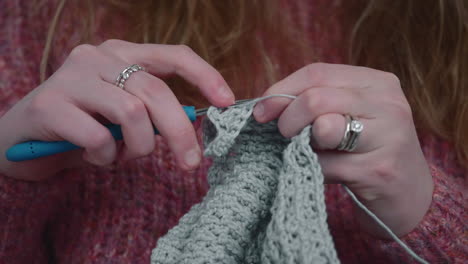 woman knits with crochet at home - female hands with hook and yarn - close up