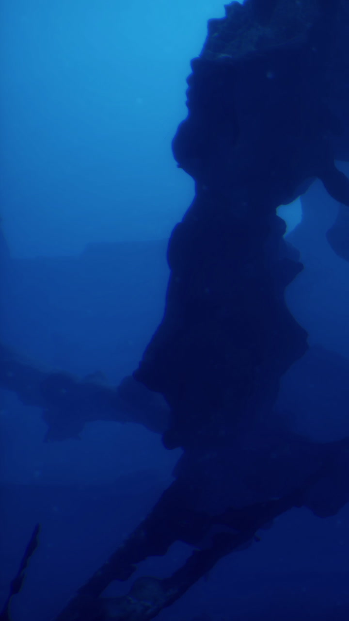 Wreckage of a sunken ship seen underwater in a dark and deep ocean