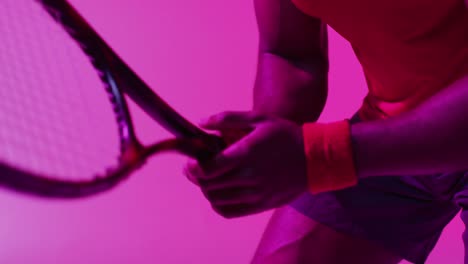 Video-of-midsection-of-african-american-female-tennis-player-on-neon-pink-lightning