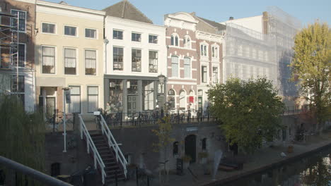 people passing beautiful old houses near dutch canal in the netherlands