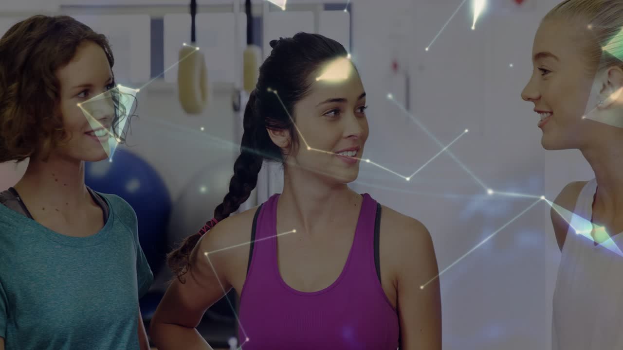 4 mujeres conversando y planificando un entrenamiento en el gimnasio mientras unas líneas animadas se difuminan formando un globo sobre el grupo.