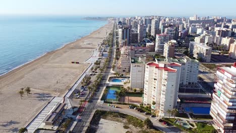 aerial drone footage of high buildings with swimming pools near the sea and beach of san juan, spain