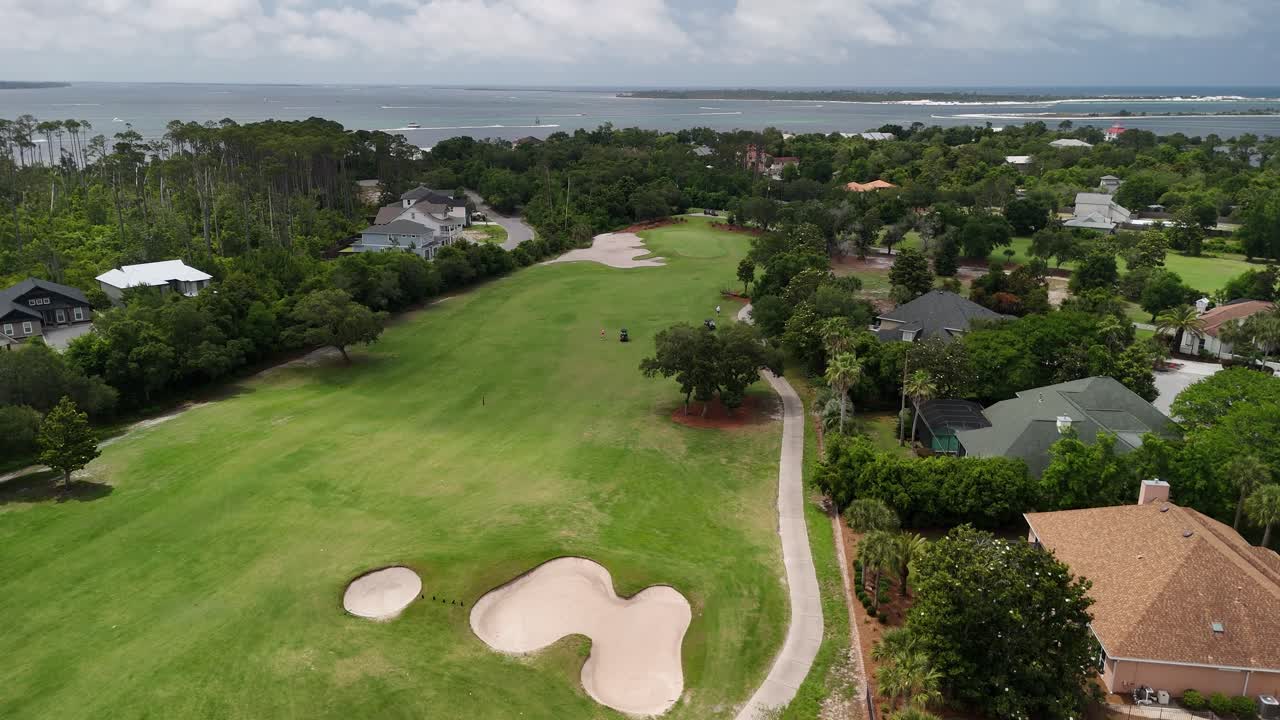 Beautiful panoramic drone movement over a green golf course park surrounded by upscale residential homes and trees, Panama City Beach, Florida, USA