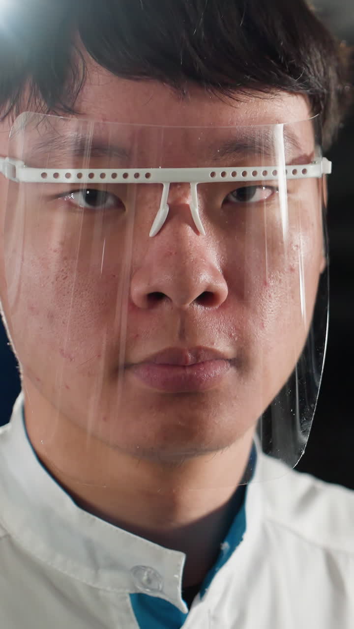 primer plano de un estudiante chino en bata de laboratorio ajustando el vidrio protector en un taller de automóviles, expresión enfocada, iluminación brillante del taller iluminando el fondo