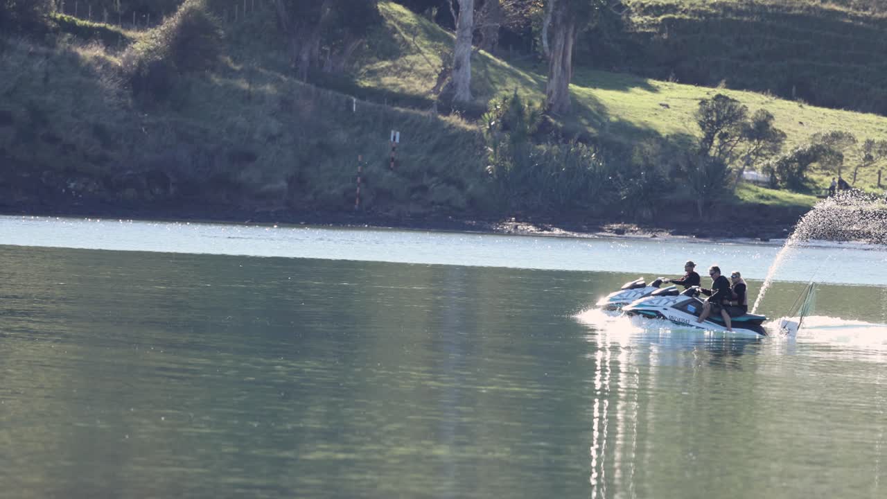 Jet ski glides across Akaroa's serene waters, creating dynamic water sprays under bright daylight