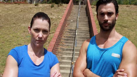 portrait of fit man and woman standing with arms crossed