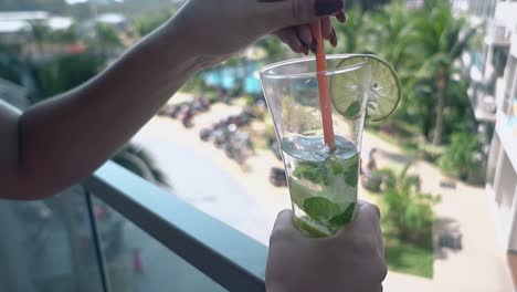 mujer se relaja en el balcón de la habitación del hotel mezclando bebidas