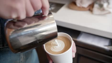 artisan cafe worker pours white cream to make dazzling cute heart in latte