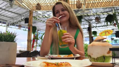 woman enjoying a drink and meal at a tropical outdoor cafe