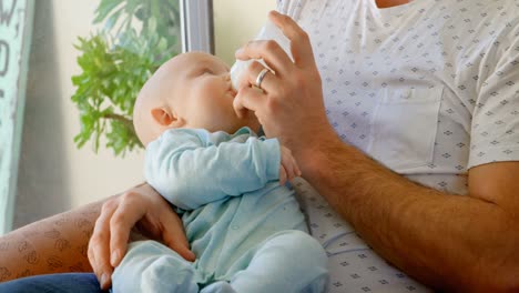 padre alimentando leche a su bebé en la sala de estar 4k