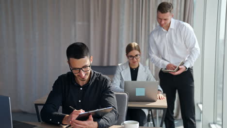 male manager talking to female employee looking at computer screen. man in black shirt working with documents thinking over the issues.