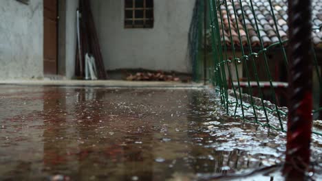 Close-up-of-drops-of-rain-fall-and-bounce-off-the-concrete-square-in-front-of-the-house