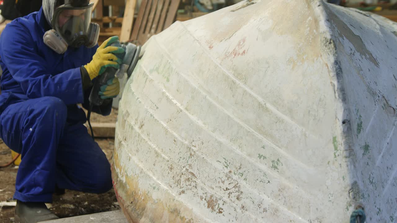 Sanding the hull of a fiberglass boat using orbital sander