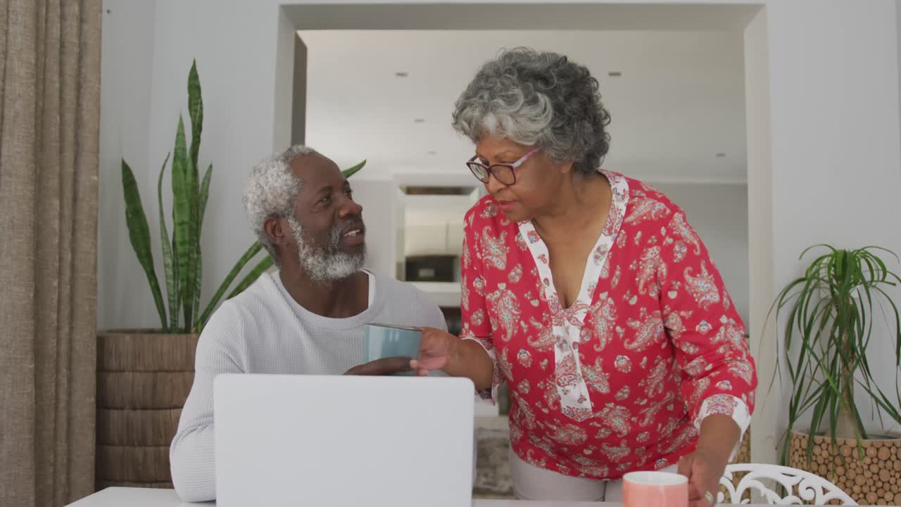 A senior African american couple spending time together at home using a laptop in social distancing