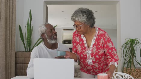 A-senior-African-american-couple-spending-time-together-at-home-using-a-laptop-in-social-distancing