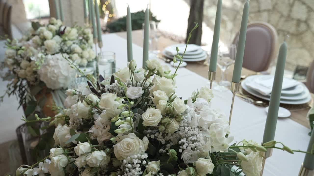 Elegant table setting with white floral centerpiece and tall, pastel candles