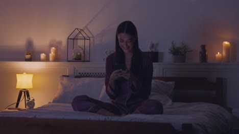 woman using phone in bed at night