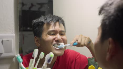 young man stands before the bathroom mirror brushing teeth with precision