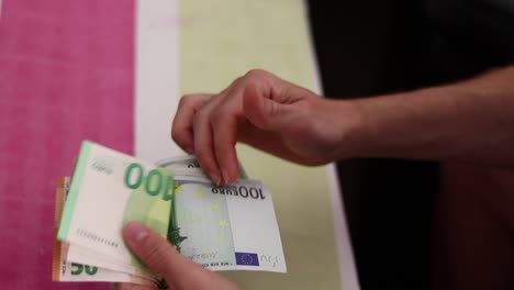 Male-hands-counting-euro-bills-of-100-and-50