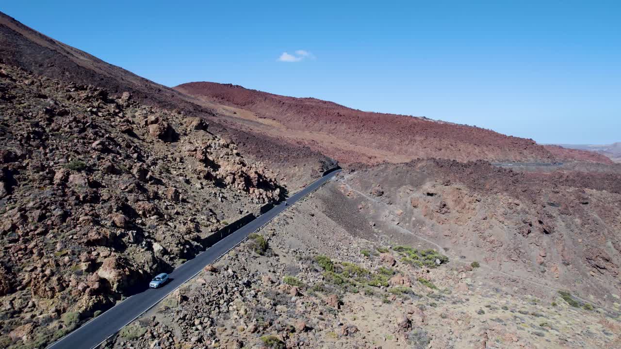 Filmato aereo in cui si sorvola una strada che attraversa campi di lava vulcanica vicino al vulcano Teide a Tenerife, con una motocicletta che attraversa un deserto. Adatto per viaggi e sfondi naturalistici suggestivi.