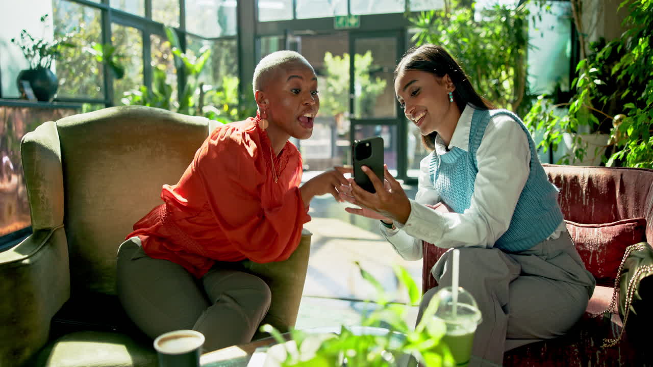 Two women talking while looking at a smartphone