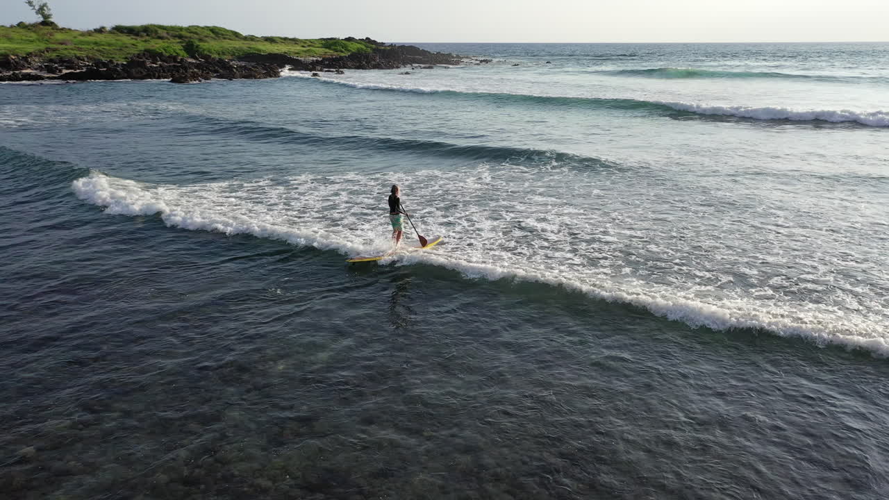 vista aérea de un paddleboarder en una tabla de sup remando en el océano en las aguas de la isla de la reunión