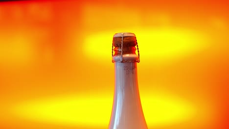 Bottle-of-champagne-isolated-on-orange-moving-background,-close-up-shot
