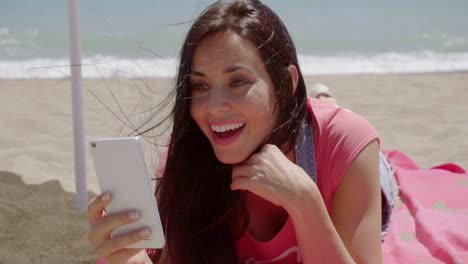mujer riendo usando el teléfono en la playa