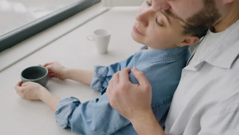 close up of a loving man tenderly hugging his girlfriend from the back at home in the morning