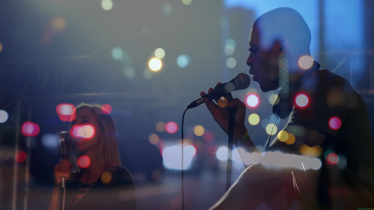 Lead vocalist raising arm on music stage, female vocalists singing with floating city light bokeh