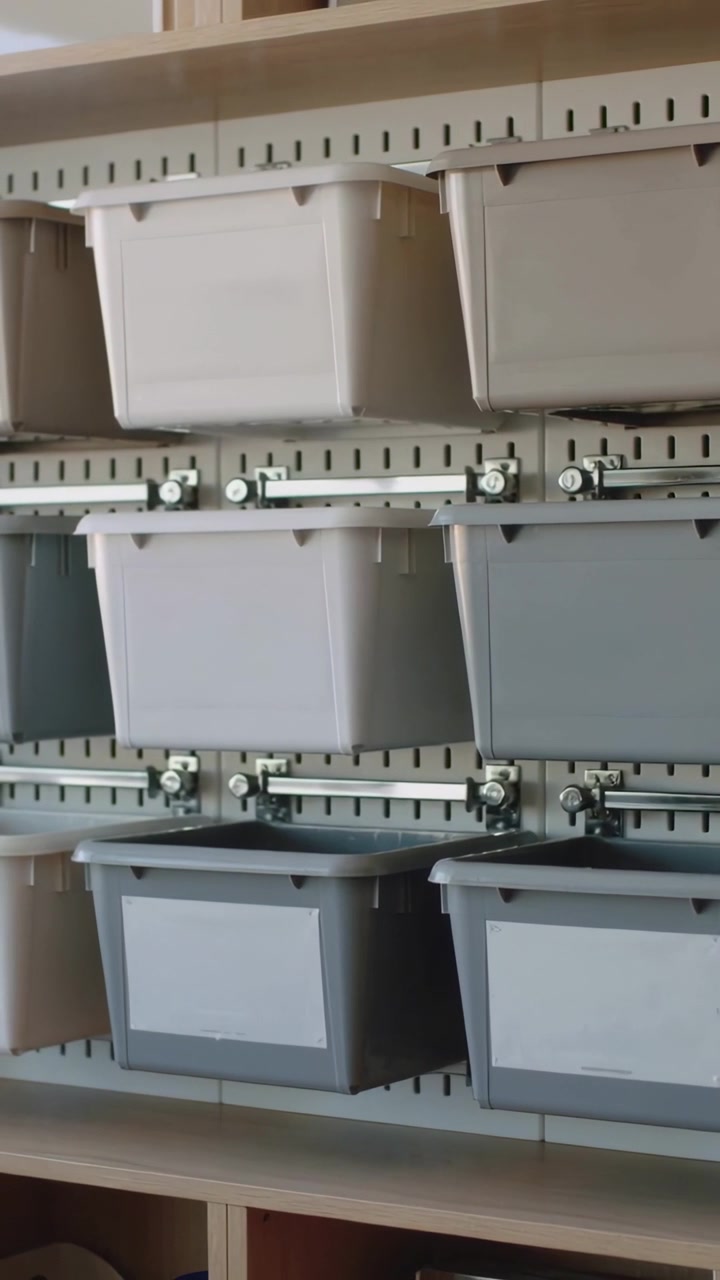 Vertical video: Shifting camera filming plastic bins on metal rails in closet for inventory