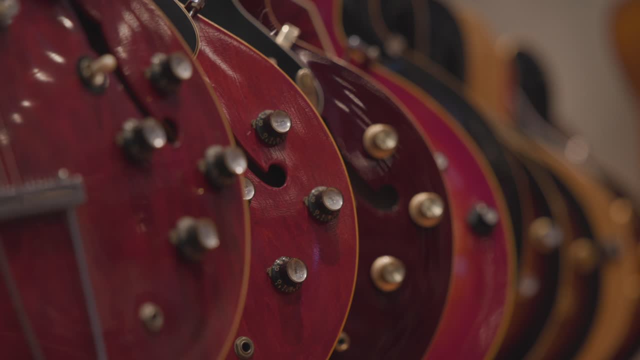 Slow motion rack focus of a line of electric guitars.