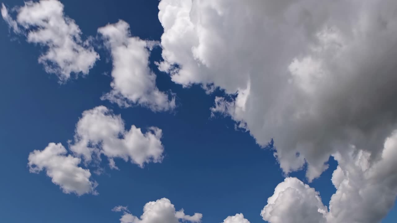 Video di soffici nuvole bianche contro un cielo blu intenso, catturate da un'angolazione bassa, creando un'atmosfera serena
