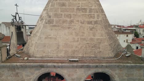 view of church bells moving up to reveal the town behind it