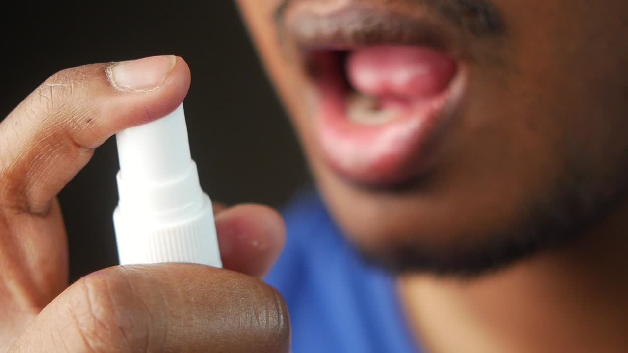 Man spraying medicine in his mouth