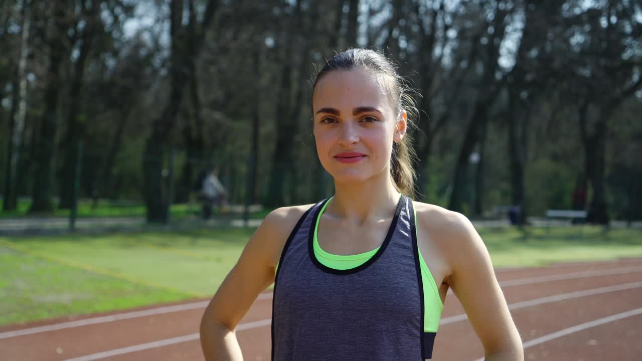 Fit and beautiful. Beautiful young woman in sports clothing smiling and looking a camera while standing outdoors