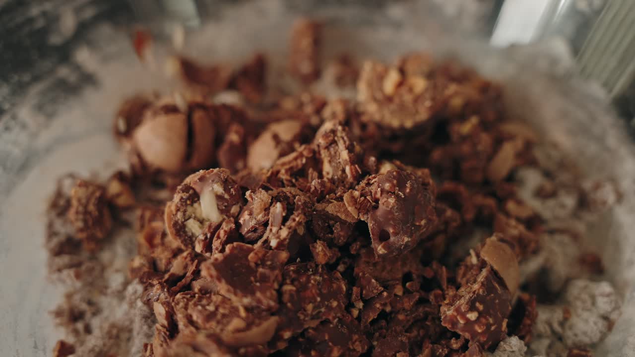 Slow motion walnuts dropping into chocolate cookie dough while mixing